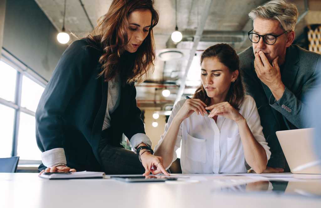 Businesswoman discussing new strategies with her team sitting around a table. Group of business people having a meeting on new project in office.